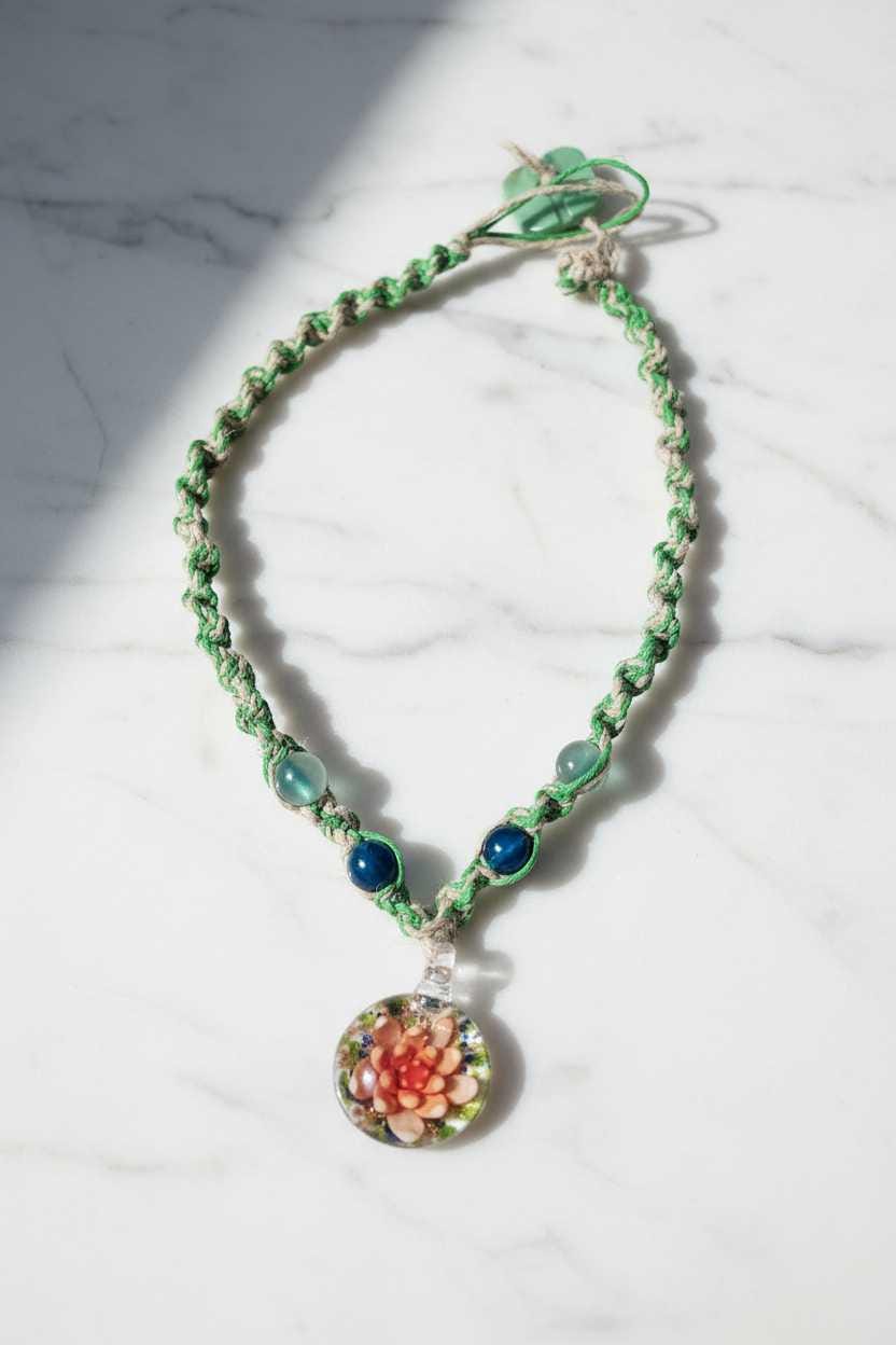 Green beaded necklace with a floral pendant on a marble surface